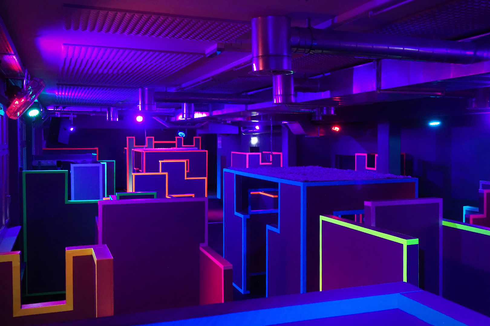 Die Arena der Blaster Arena Hohenems ausgestattet mit verschiedensten Deckungsmöglichkeiten im Zinnendesign im "Dark-Mode" unter Schwarzlicht.