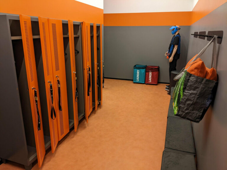 Garderobe der Blaster Arena Hohenems mit orangen Spints und einer Sitzbank.